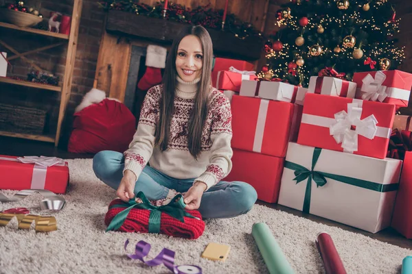 나무 근처에 있는 카펫 팩에 앉아 있는 귀여운 젊은 숙녀의 사진은 실내에서 크리스마스 선물로 양말을 신고 있다. — 스톡 사진