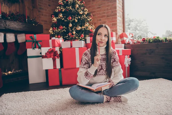 Pleine taille photo de rêve jeune femme écrire liste asseoir près de l'arbre actuel porter pull jeans chaussettes Noël à la maison — Photo