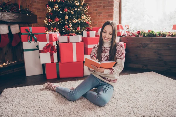 Foto av glänsande drömmande mogen kvinna bära tryck tröja leende läsning jul saga inomhus hus hem rum — Stockfoto
