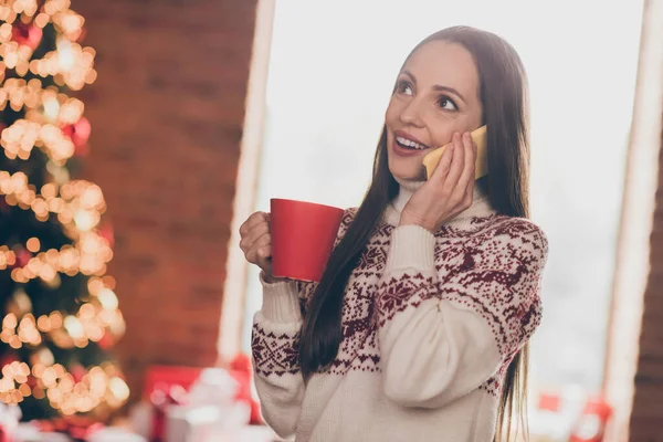 Foto de divertida joven impresionada hablar teléfono beber té cerca del árbol usar suéter feo año nuevo en casa —  Fotos de Stock