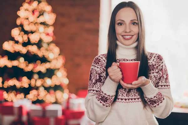 Portré vonzó vidám nő visel meleg pulóver ivás ital töltő ünnepi nap díszített otthon beltérben — Stock Fotó