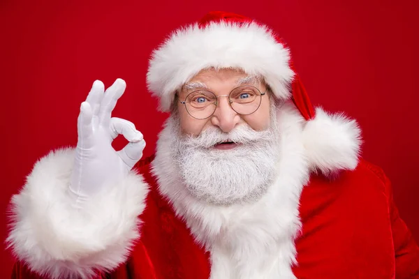 Foto de homem aposentado animado engraçado usar óculos de traje de Papai Noel sorrindo mostrando okey sinal isolado cor vermelha fundo — Fotografia de Stock