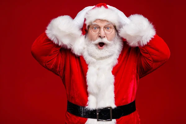 Foto van onder de indruk geschokte man gepensioneerde gekleed santa claus kostuum riem armen hoofd open mond geïsoleerde rode kleur achtergrond — Stockfoto