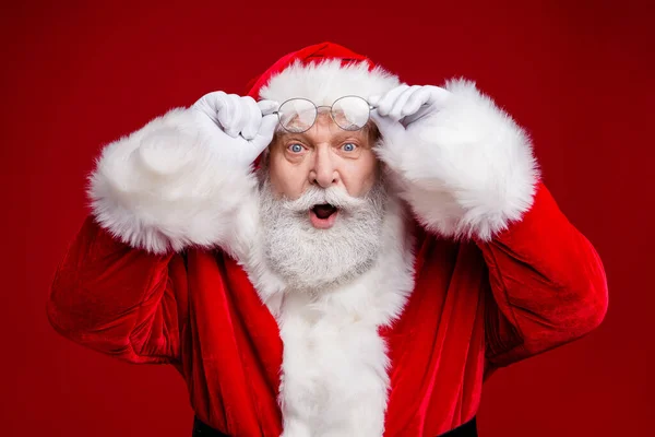Photo of amazed surprised retired man wear santa claus costume arms spectacles open mouth isolated red color background — Stock Photo, Image