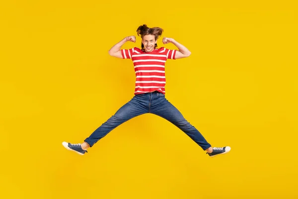 Foto von charmanten starken jungen Mann gekleidet rotes T-Shirt springen hoch zeigt Muskeln lächeln isoliert gelbe Farbe Hintergrund — Stockfoto