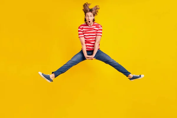 Foto di impressionato divertente giovane uomo indossare a strisce t-shirt salto alto isolato colore giallo sfondo — Foto Stock