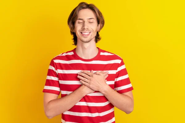 Foto av drömmande söt ung kille klädd röd t-shirt leende armar bröstet stängda ögon isolerad gul färg bakgrund — Stockfoto