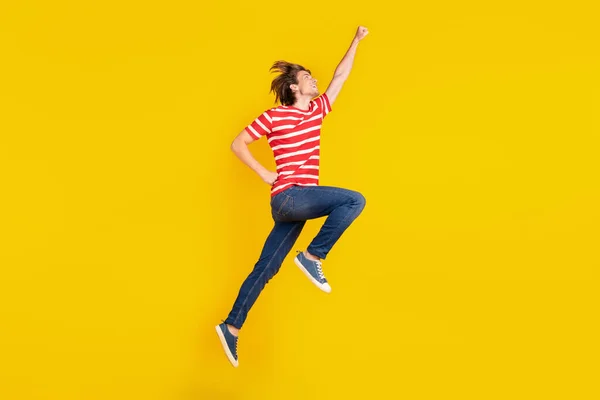 Foto von niedlichen starken jungen Mann tragen gestreifte T-Shirt springen hoch suchen leeren Raum isoliert gelbe Farbe Hintergrund — Stockfoto
