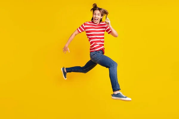 Foto von ziemlich süßen jungen Kerl gekleidet rotes T-Shirt läuft Springen modernes Gerät lächelnd isoliert gelbe Farbe Hintergrund — Stockfoto