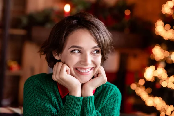 Φωτογραφία από αξιολάτρευτο γλυκό νεαρή γυναίκα ντυμένος πλεκτό πουλόβερ χέρια μάγουλα χαμογελώντας εσωτερικό δωμάτιο σπίτι — Φωτογραφία Αρχείου