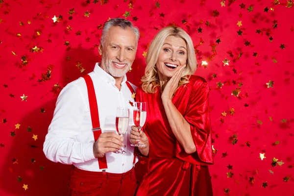 興奮した引退したカップルのセルペンチンイベントの写真赤い色の背景に隔離されたシャンパンノエルの雰囲気 — ストック写真