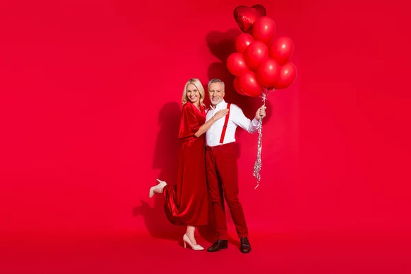 Фотографія повнорозмірного хлопця на пенсії романтичного калюжа відчуває багато повітряних кульок підтяжки ізольовані на червоному тлі — стокове фото