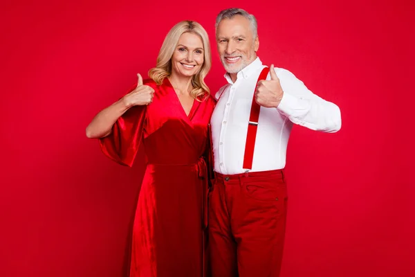 Foto de esposa mayor marido mostrar pulgar-up consejo elección x-mas evento desgaste vestido elegante aislado sobre fondo de color rojo —  Fotos de Stock