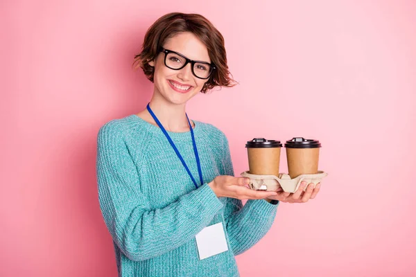 Foto de agradável otimista encaracolado morena penteado senhora segurar óculos de desgaste do café camisola azul isolado no fundo cor-de-rosa — Fotografia de Stock