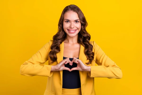 Портрет привабливої веселої хвилястої жінки, що показує знак серця наживо ізольований на яскраво-жовтому кольоровому фоні — стокове фото
