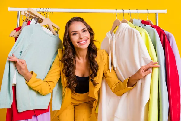Zdjęcie dość atrakcyjne młoda kobieta ubrana marynarka garnitur uśmiecha się kupując nowe ubrania odizolowane żółty kolor tła — Zdjęcie stockowe