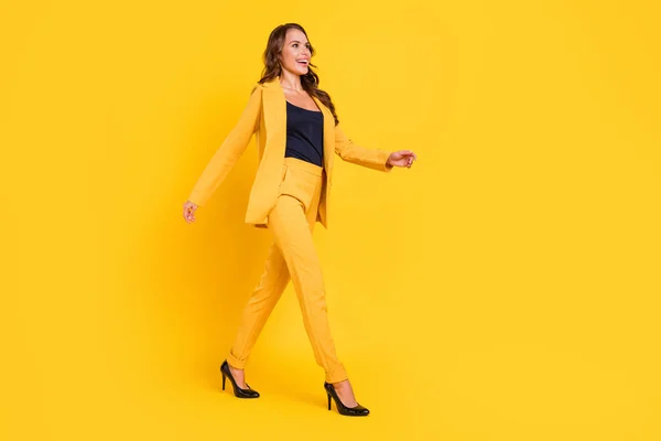 Foto de adorable joven brillante vestido traje chaqueta sonriente caminando buscando espacio vacío aislado color amarillo fondo — Foto de Stock