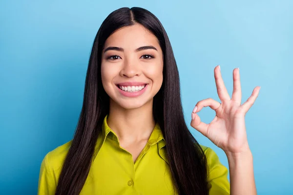 Photo of young girl happy positive smile show fingers okay sign alright deal cool ad isolated over blue color background — Stock Photo, Image