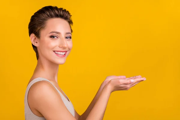 Foto de la encantadora señora bonita de la palma de la mano espacio vacío sonrisa blanca desgaste gris superior aislado color amarillo fondo —  Fotos de Stock