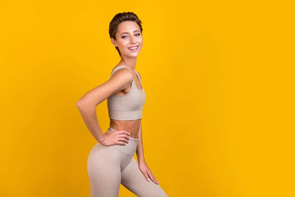 Foto de mujer tierna positiva mano cintura posando radiante sonrisa desgaste gris superior aislado color amarillo fondo —  Fotos de Stock