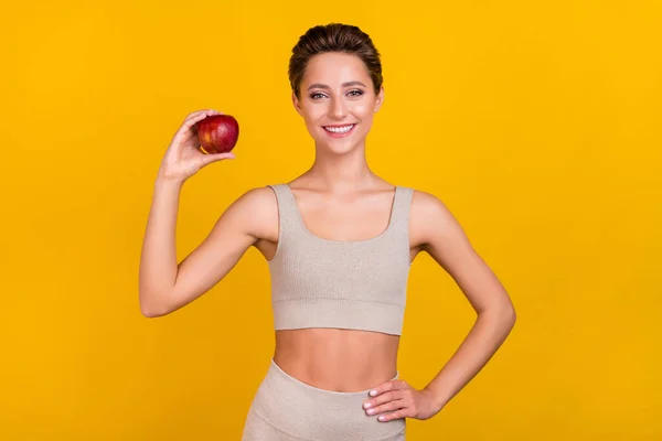 Retrato de chica alegre deportiva atractiva sosteniendo en manzana menú de dieta útil almuerzo aislado sobre fondo de color amarillo brillante —  Fotos de Stock