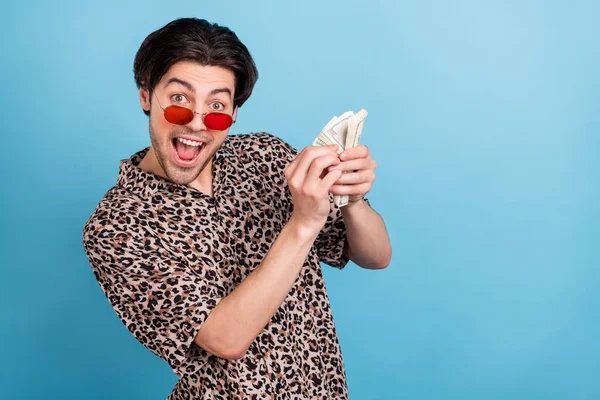 Retrato de atraente surpreendido alegre cara contando-nos dólares ganhar vencedor isolado sobre fundo de cor azul brilhante — Fotografia de Stock