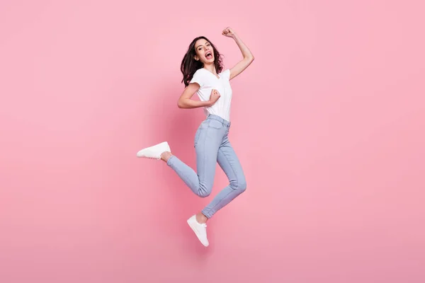 행복 한 젊은 여성 이 주먹을 들어 올리는 사진 전체가 핑크 색 배경 위에 고립된 채뛰어오르고 있다 — 스톡 사진