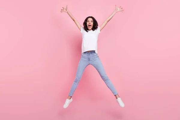 Фотографія повного тіла красивої молодої активної веселої жінки, що стрибає вгору, піднімає божевільний настрій ізольовано на рожевому кольорі — стокове фото