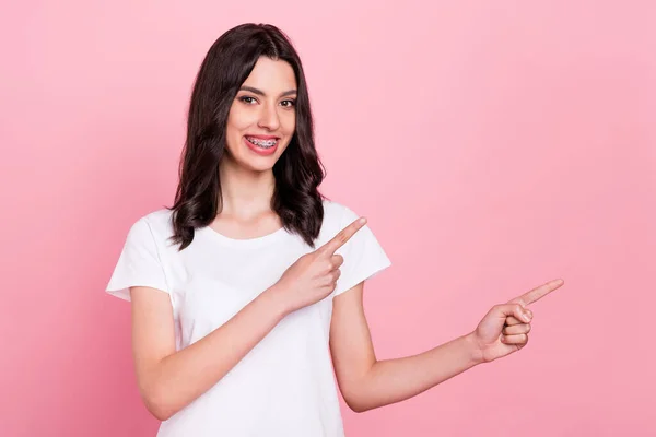 Foto di positivo giovane donna affascinante felice punta il dito dello spazio vuoto sorriso isolato su sfondo di colore rosa — Foto Stock
