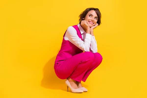Fotografie rozkošné přemýšlivý mladá dáma nosit růžový oblek sedí hledá prázdný prostor usmívá izolované žluté barvy pozadí — Stock fotografie