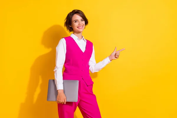 Portrait of attractive cheerful girl holding laptop showing copy empty blank space isolated over bright yellow color background — Stock Photo, Image