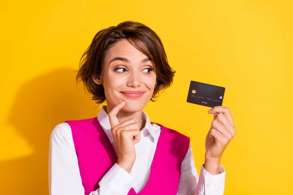 Foto de doce e complicado jovem senhora usar terno rosa segurando olhando banco cartão dedo queixo isolado cor amarela fundo — Fotografia de Stock