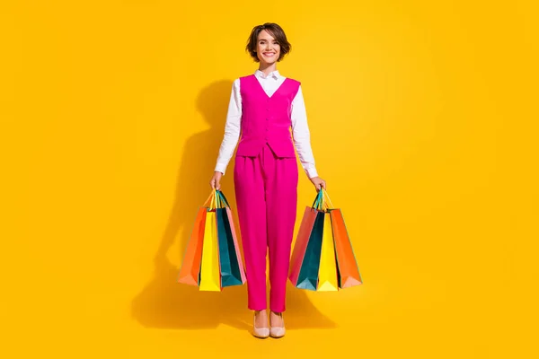 Photo of pretty charming young lady wear pink suit holding bargains smiling isolated yellow color background — Stock Photo, Image