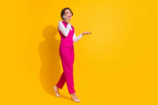 Teljes test fotó szép Y-generációs barna hölgy megy beszélni telefonon viselni rózsaszín öltöny tűsarkú elszigetelt sárga háttér — Stock Fotó