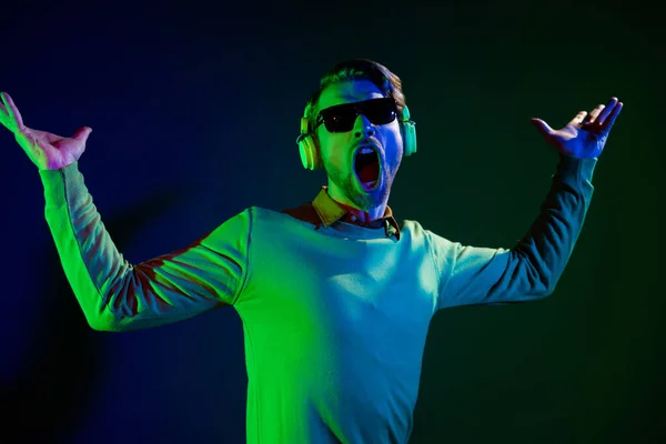 Φωτογραφία του funky νεαρός χαρούμενος άνθρωπος φορούν γυαλιά ηλίου headset καλή διάθεση τραγουδούν clubber απομονώνονται σε νέον φόντο — Φωτογραφία Αρχείου