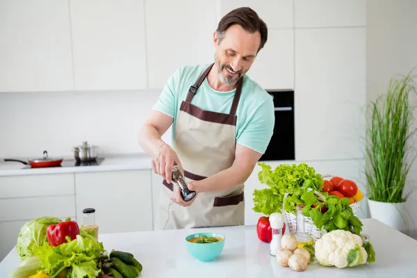 Neşeli adamın aşçı püre çorbası biber kutusu baharatları önlük mavi tişört ve ev mutfağı. — Stok fotoğraf