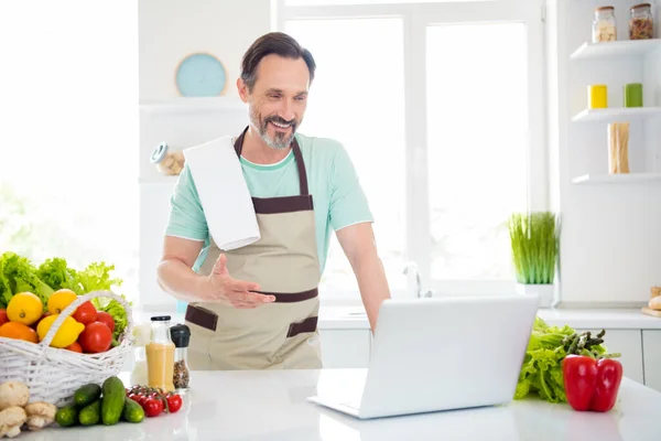 Foto de confiante bom homem olhar tela laptop vídeo chamada lição desgaste avental azul t-shirt casa cozinha dentro de casa — Fotografia de Stock