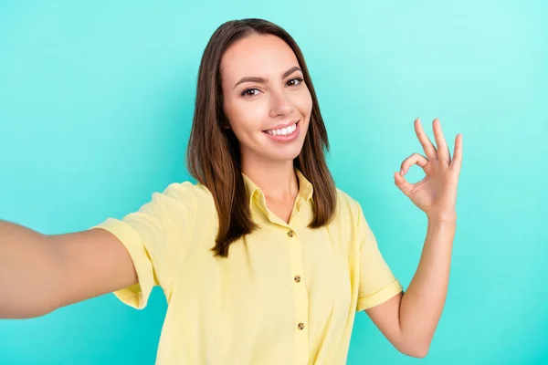 Foto de impressionado milenar senhora morena fazer selfie show okey desgaste amarelo top isolado no fundo cor teal — Fotografia de Stock