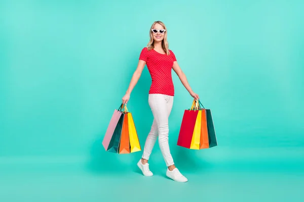 Teljes méretű profil oldalán fotó fiatal nő boldog pozitív mosoly megy tartsa bevásárló táskák elszigetelt türkiz szín háttér — Stock Fotó