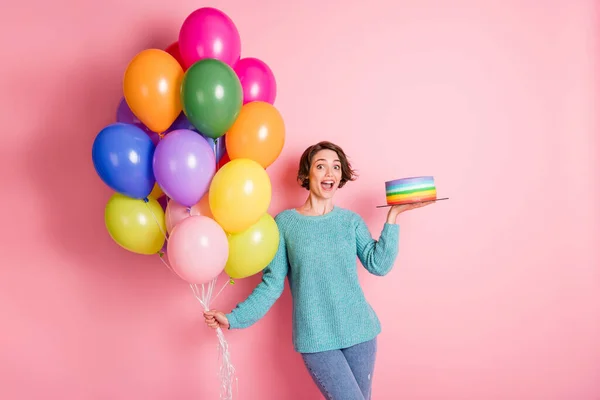 Foto de la optimista morena rizada peinado dama celebrar globos pastel desgaste pantalones vaqueros suéter azul aislado sobre fondo de color rosa — Foto de Stock