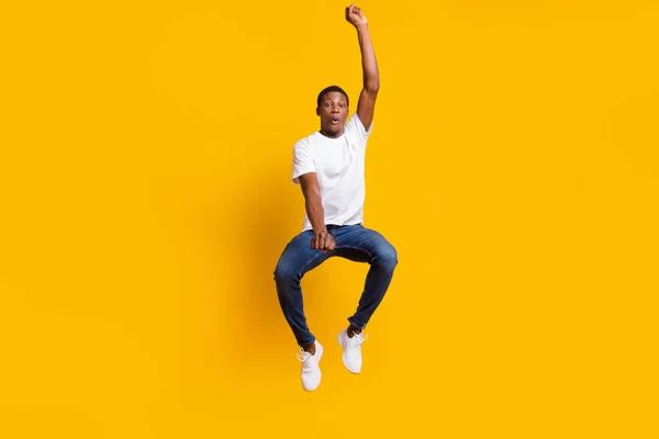 Foto em tamanho completo de cool morena millennial cara salto desgaste branco t-shirt jeans isolado no fundo de cor amarela — Fotografia de Stock