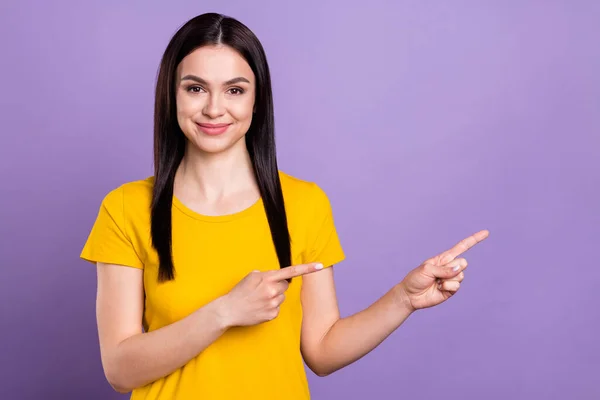 Foto de encantadora jovem brilhante usar roupa amarela apontando dois dedos espaço vazio sorrindo isolado cor violeta fundo — Fotografia de Stock