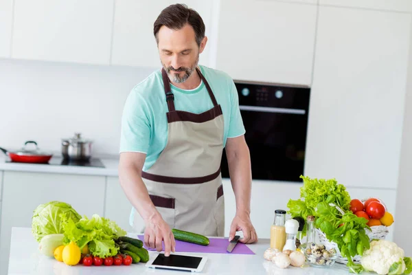 Erkeksi erkek aşçı salatasının fotoğrafı. Video tableti, önlük, mavi tişört, ev mutfağı. — Stok fotoğraf