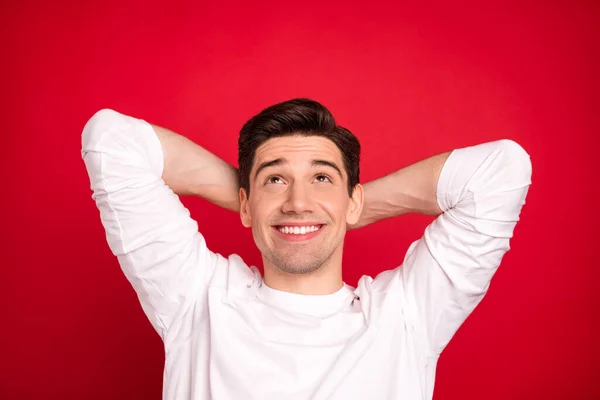 Bilde av en morsom brunet ung fyr som ser opp på hendene, bruker hvit skjorte isolert på rød bakgrunn – stockfoto