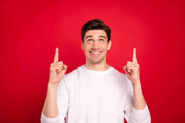 Photo of curious brunet young guy point up wear white shirt isolated on red color background — Stock Photo, Image