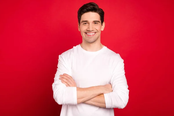 Foto retrato morena chico en camisa blanca confiado sonriendo cruzado manos aislado vívido color rojo fondo —  Fotos de Stock