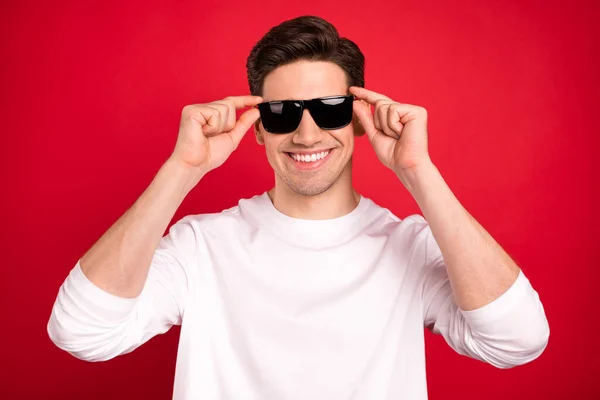 Foto di fresco brunet giovane ragazzo mani occhiali camicia bianca isolato su sfondo di colore rosso — Foto Stock