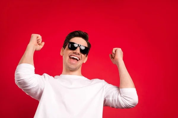Foto di hooray brunet millennial ragazzo mani pugni indossare occhiali camicia bianca isolato su sfondo di colore rosso — Foto Stock