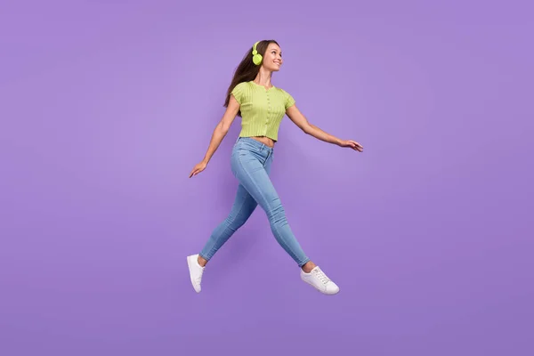 Vista completa del tamaño del cuerpo de una chica bastante alegre saltando escuchando melodía que se aísla sobre el fondo violeta violeta — Foto de Stock