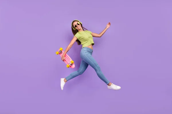 Longitud completa vista del tamaño del cuerpo de la chica alegre agradable de moda saltando escuchando la canción que se divierte ir aislado sobre el color violeta púrpura de fondo — Foto de Stock